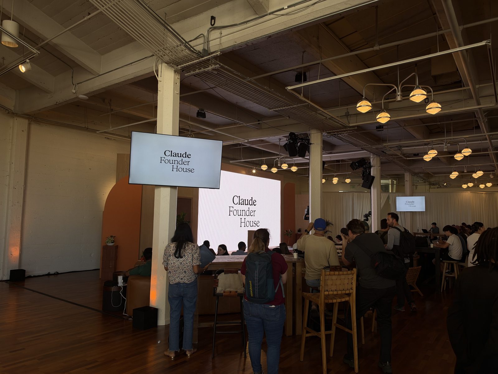 Founders gathered in the main hall at Claude Founder House, with Claude Founder House signage on screens.