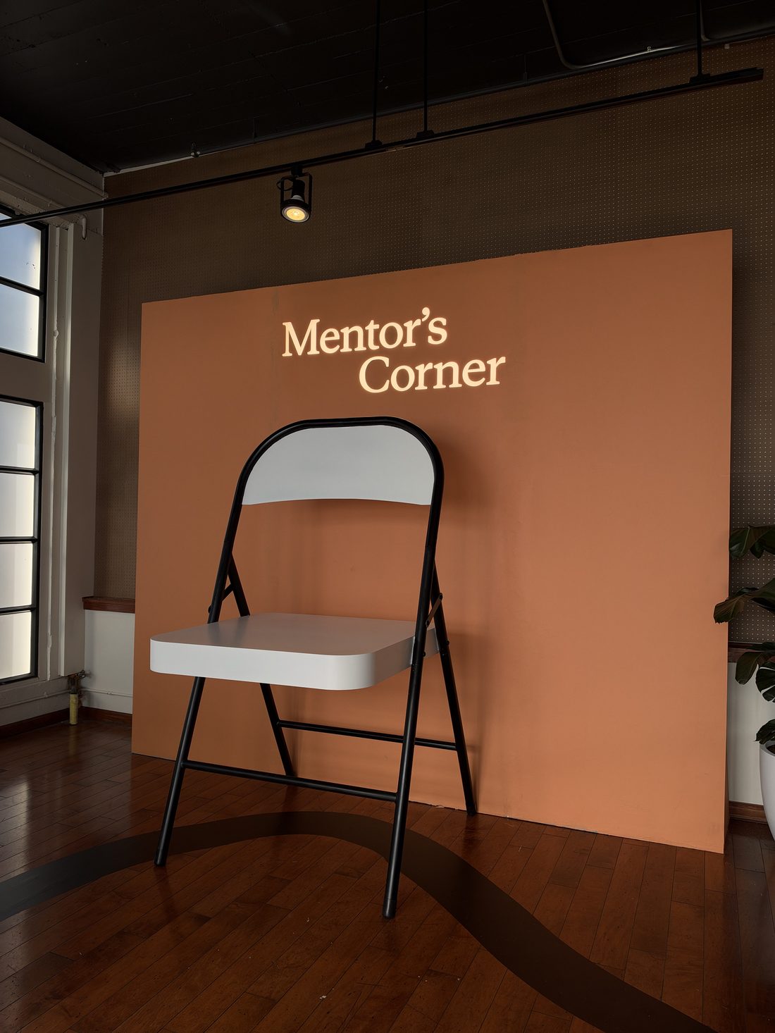 Mentor's Corner at Claude Founder House, an oversized white folding chair in front of an orange wall.